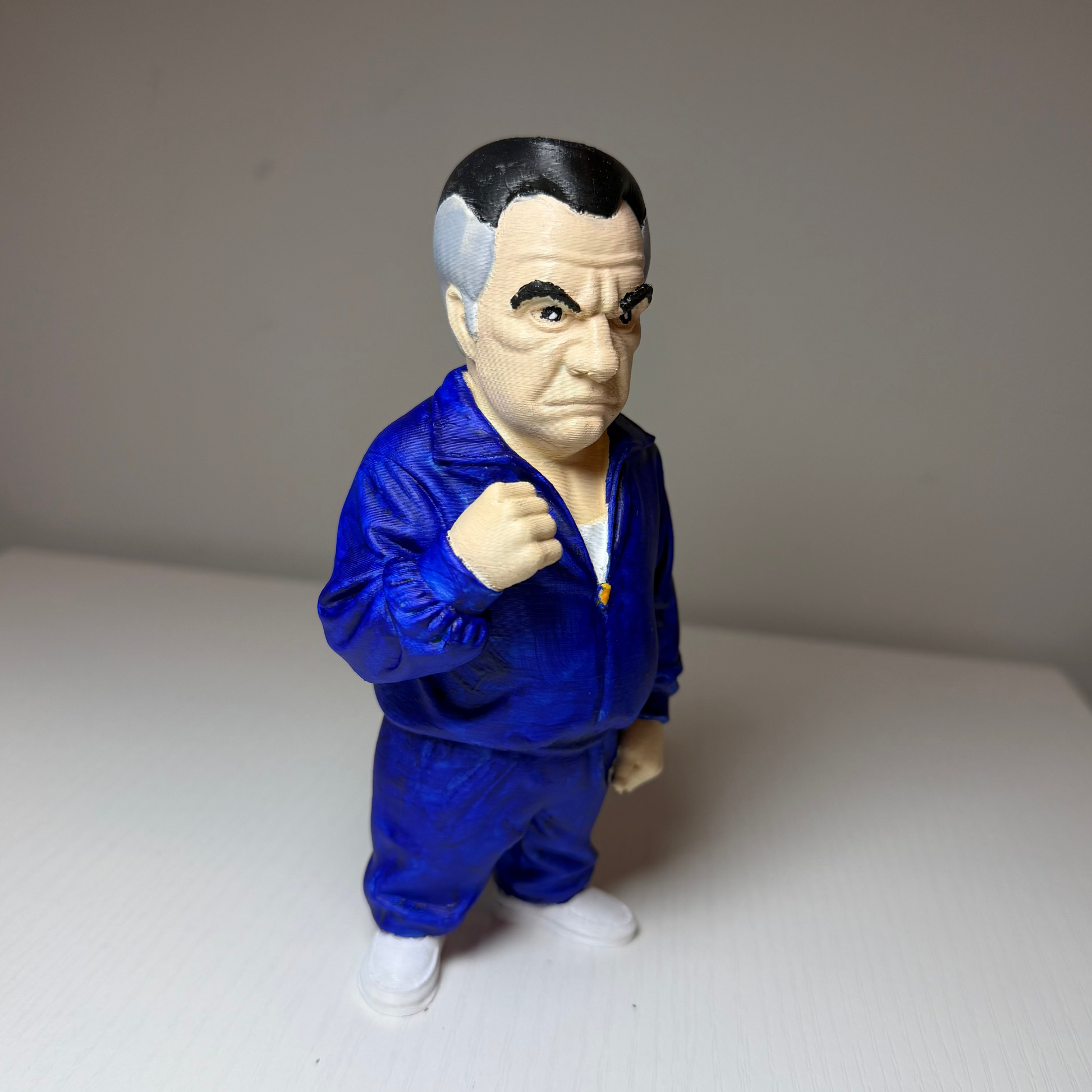 Paulie Walnuts Action figure from The Sopranos in a blue tracksuit on a plain background