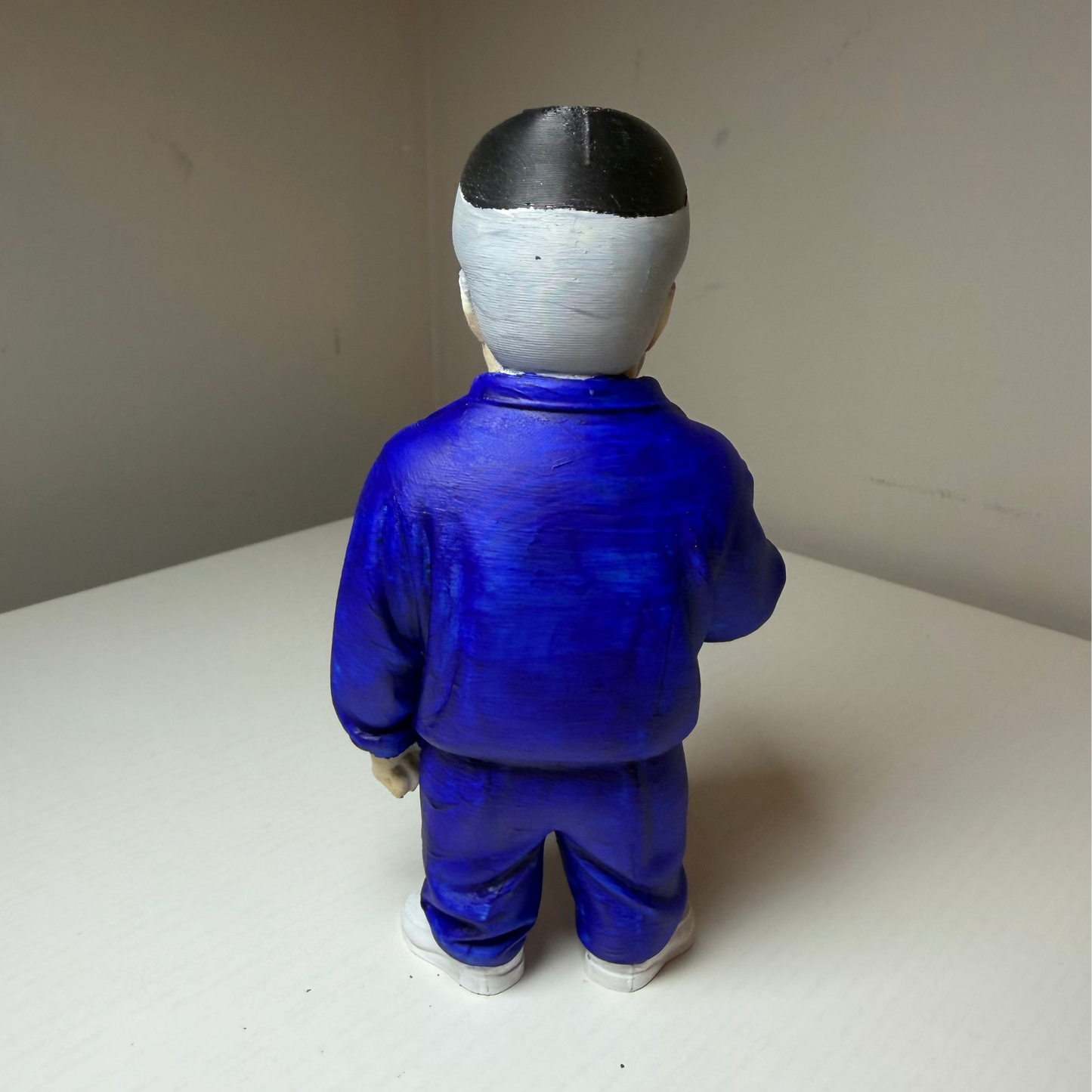 Paulie Walnuts Action figure from The Sopranos in a blue tracksuit on a plain background