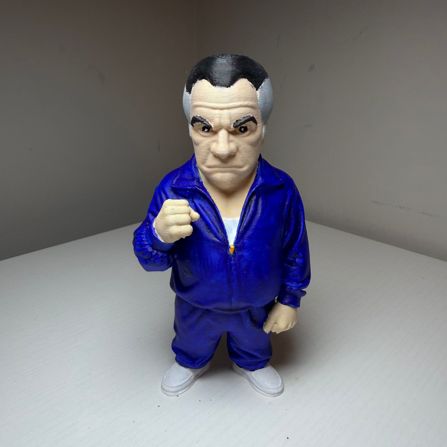 Paulie Walnuts Action figure from The Sopranos in a blue tracksuit on a plain background