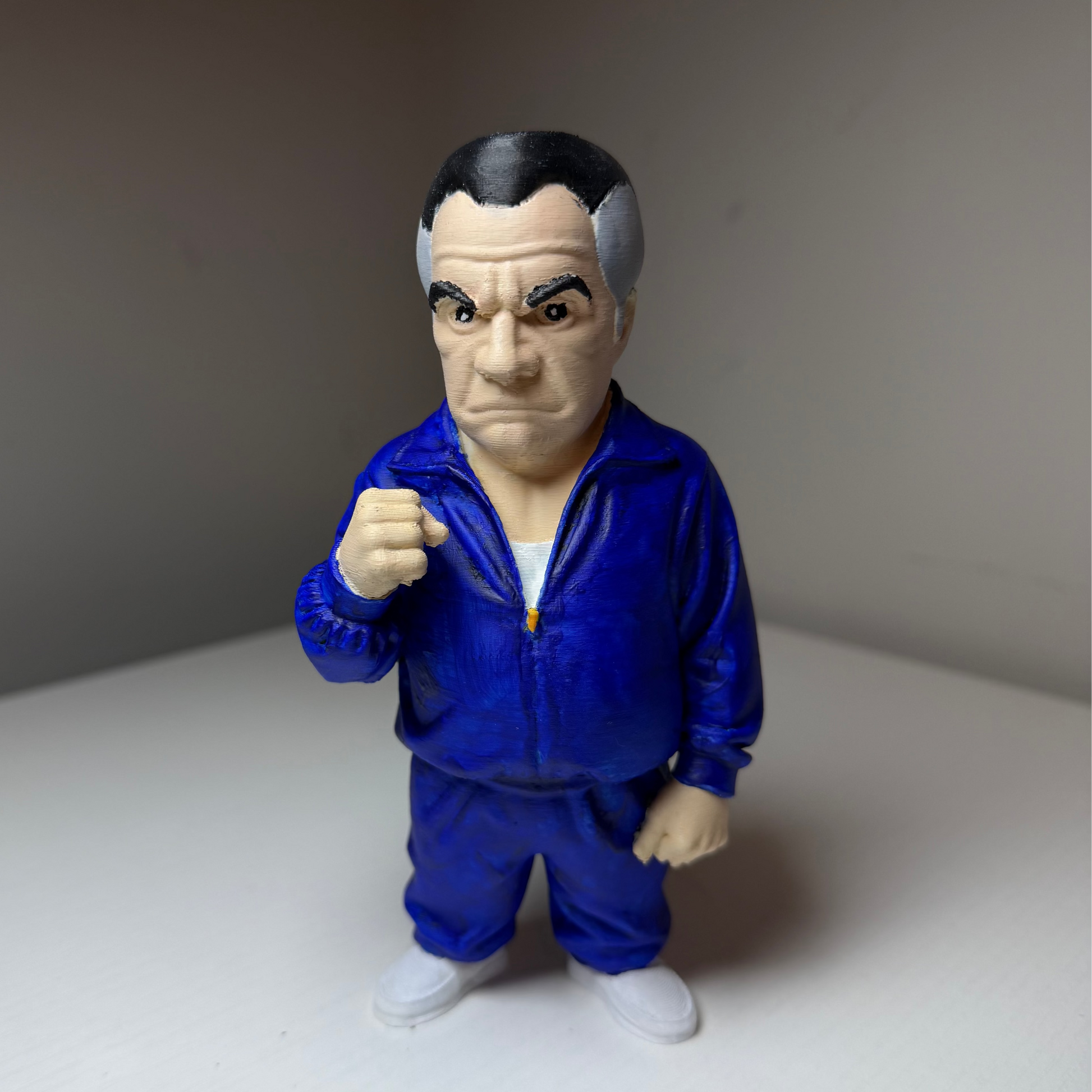 Paulie Walnuts Action figure from The Sopranos in a blue tracksuit on a plain background